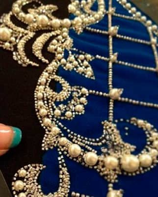 Bordado artístico con canutillos plateados y perlas sobre tela azul y negra