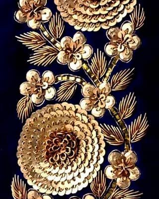 Bordado floral con lentejuelas doradas y pedrería sobre tela azul oscuro