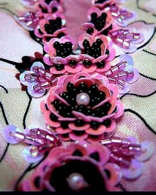 Bordado floral con lentejuelas rosadas, mostacilla negra y canutillos iridiscentes.