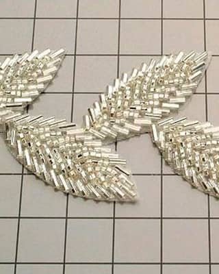 Aplicación de hojas bordadas con canutillo plateado, técnica de relleno de pedrería.