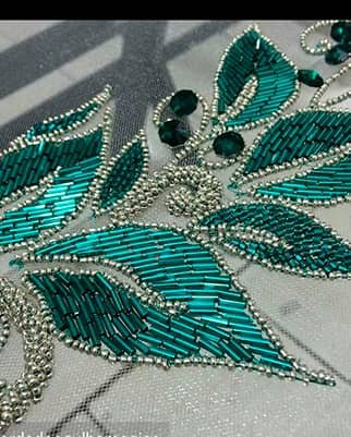 Aplicación de hojas bordadas con canutillo verde esmeralda y contorno de mostacilla plateada.