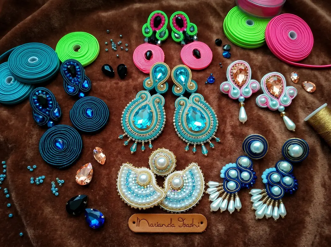 Alumna mostrando aretes creados en el curso de joyeria bordada en pedreria